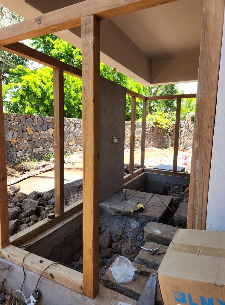 Timber posts and beams being installed beside a house and garden